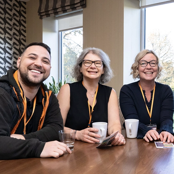 Emma and the team smiling around a table.